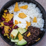 Mexikanische Burrito Bowl mit Mais, Kidneybohnen, Avocado, Reis und Limetten-Schmand