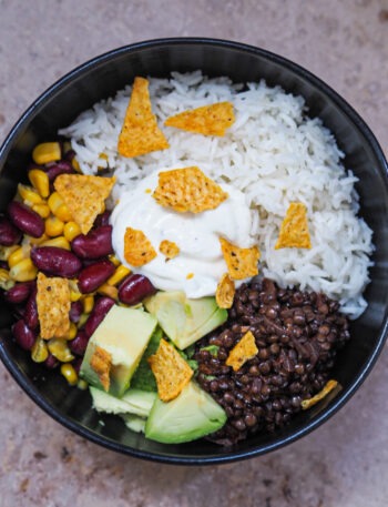 Mexikanische Burrito Bowl mit Mais, Kidneybohnen, Avocado, Reis und Limetten-Schmand